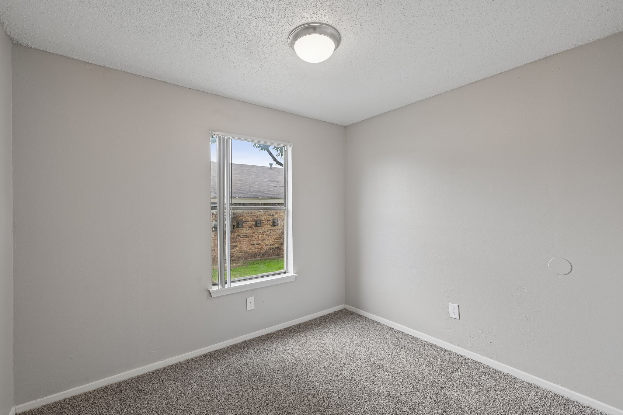 A room with a window and a ceiling light.